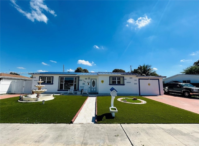 single story home featuring metal roof, an attached garage, a standing seam roof, decorative driveway, and a front lawn