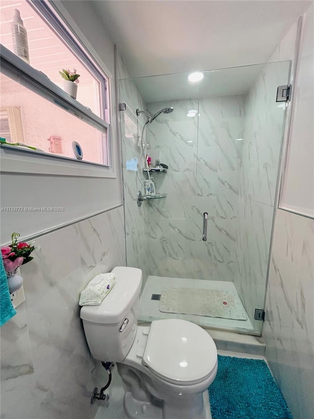 full bath featuring toilet, a marble finish shower, and tile walls