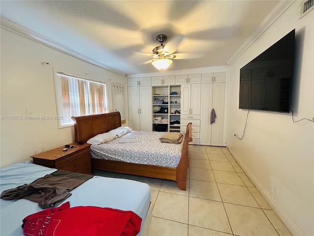 bedroom featuring a textured ceiling, light tile patterned flooring, visible vents, baseboards, and ornamental molding