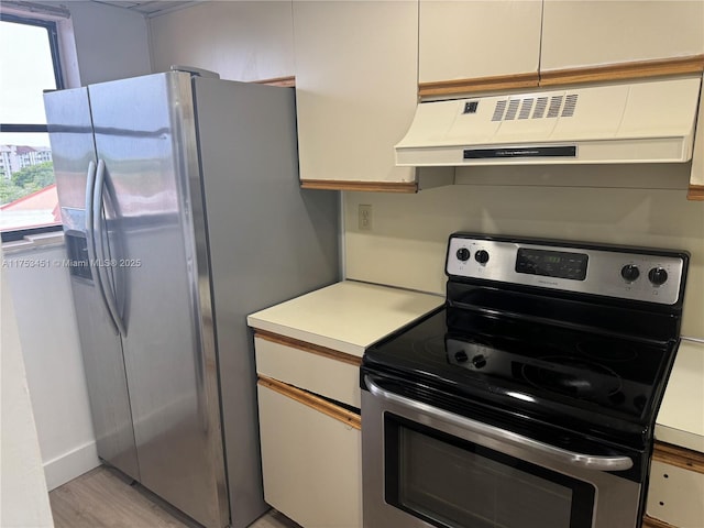 kitchen with appliances with stainless steel finishes, light countertops, light wood-style flooring, and extractor fan