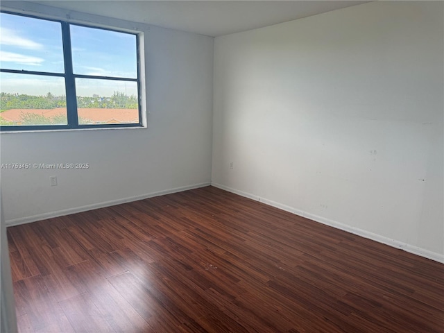 unfurnished room with baseboards and wood finished floors