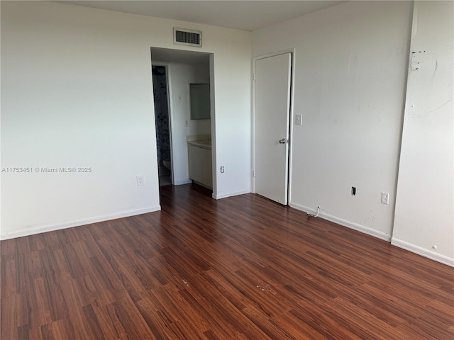 unfurnished room with dark wood-style flooring, visible vents, and baseboards