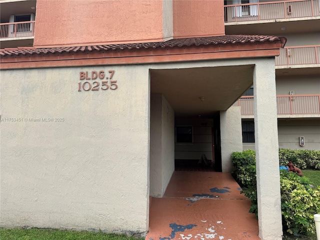 property entrance featuring a tile roof and stucco siding