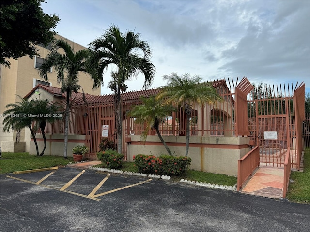 view of building exterior with uncovered parking and fence