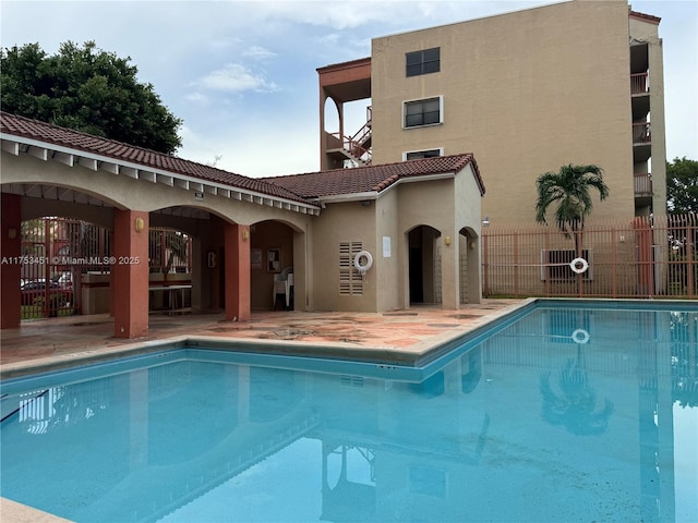 pool with a patio and fence