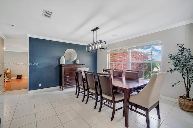 dining area with light tile patterned floors, baseboards, visible vents, and crown molding