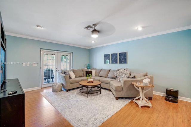 living area with baseboards, visible vents, wood finished floors, crown molding, and french doors