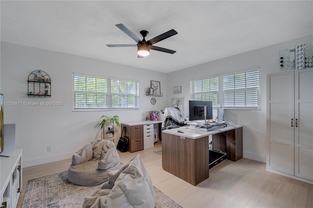 home office featuring ceiling fan, light wood finished floors, baseboards, and a textured ceiling