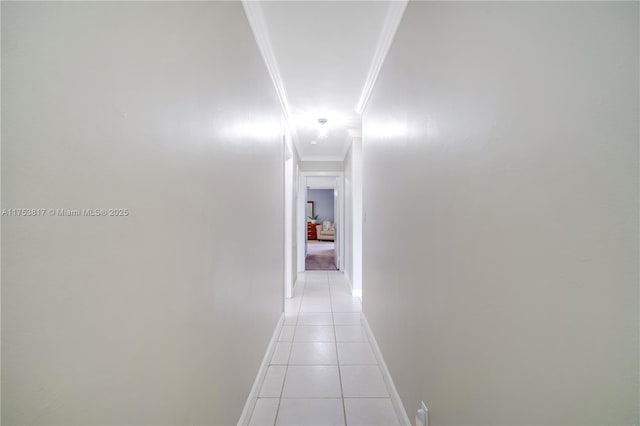 corridor with baseboards, light tile patterned flooring, and crown molding