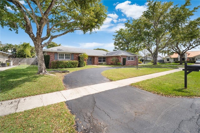 ranch-style house with driveway, brick siding, a front lawn, and fence