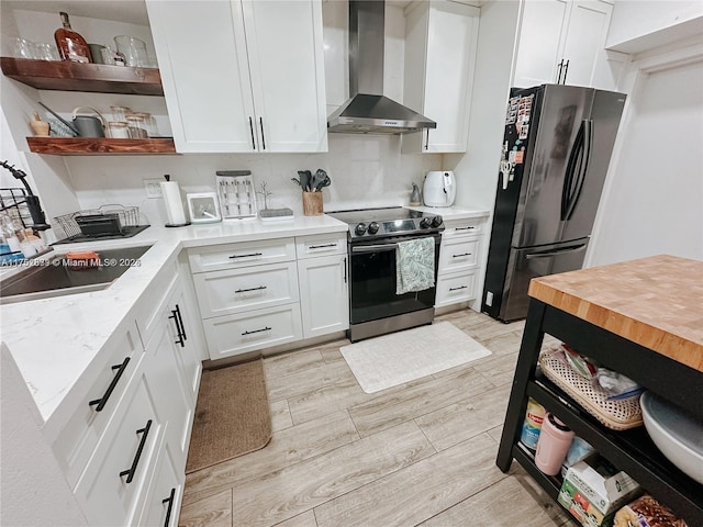 kitchen with open shelves, stainless steel appliances, light wood-style floors, white cabinets, and wall chimney range hood