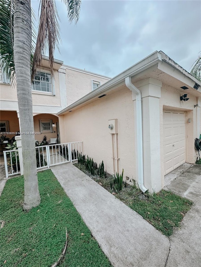 view of property exterior with a gate, an attached garage, and stucco siding