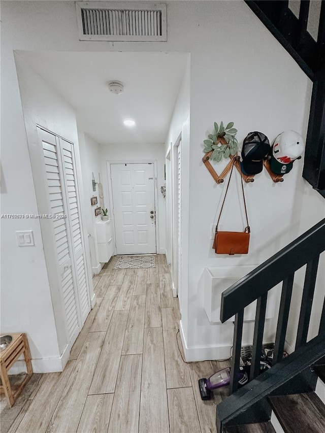 hallway featuring wood tiled floor, visible vents, and baseboards