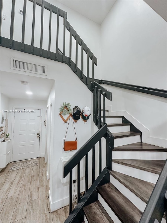 stairs featuring wood finished floors, visible vents, and baseboards