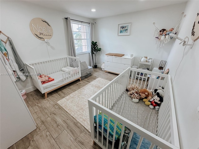 bedroom with a crib, baseboards, and wood finished floors