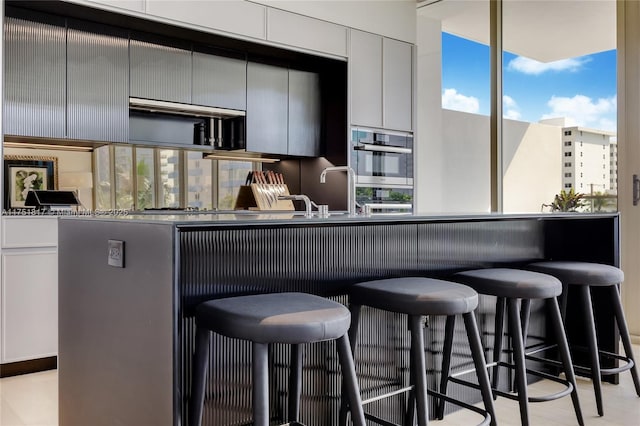 kitchen with double oven, a sink, and a kitchen breakfast bar