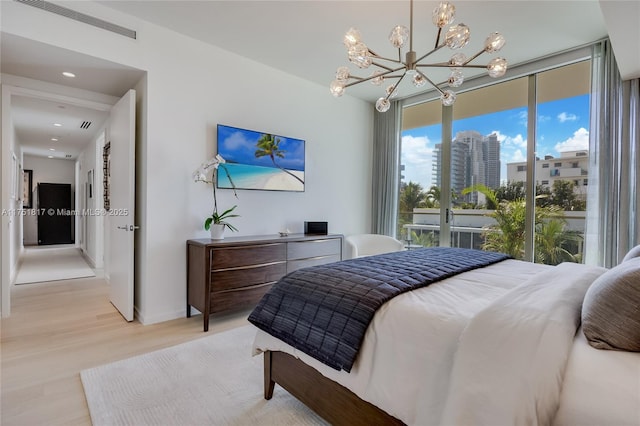 bedroom featuring a notable chandelier, visible vents, access to outside, light wood finished floors, and a wall of windows