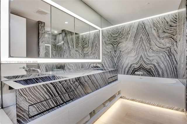 full bathroom featuring double vanity, a freestanding tub, walk in shower, and visible vents