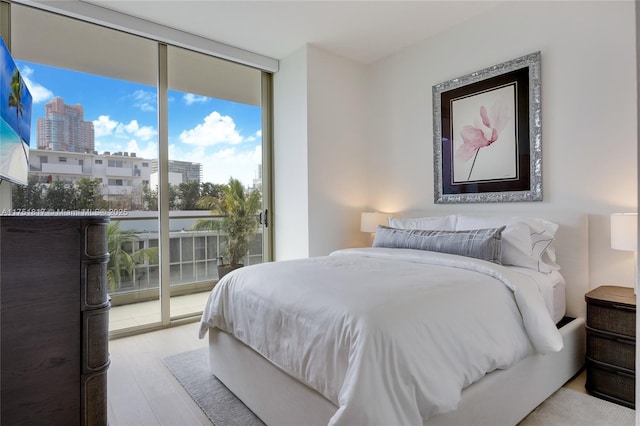 bedroom featuring a wall of windows, access to exterior, and wood finished floors