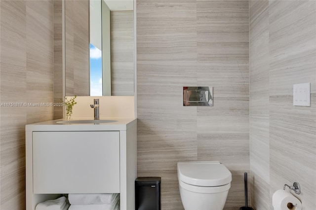 half bathroom with tile walls, toilet, and vanity