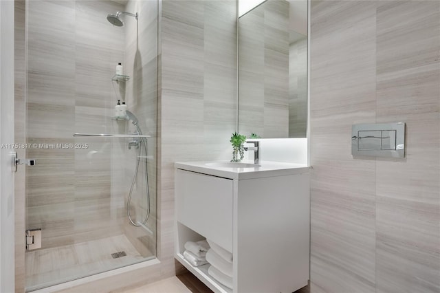 full bathroom featuring a shower stall, tile walls, and vanity