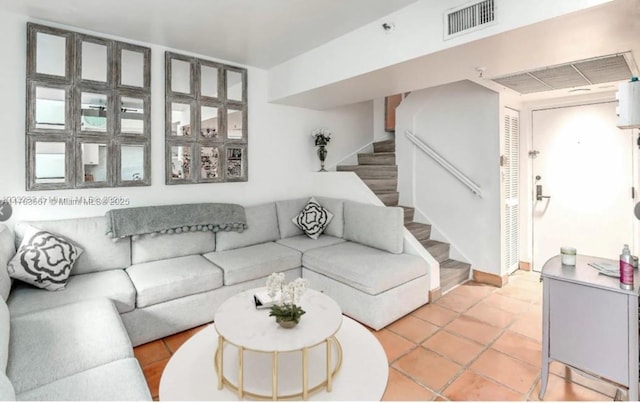 living area featuring light tile patterned floors, stairway, and visible vents