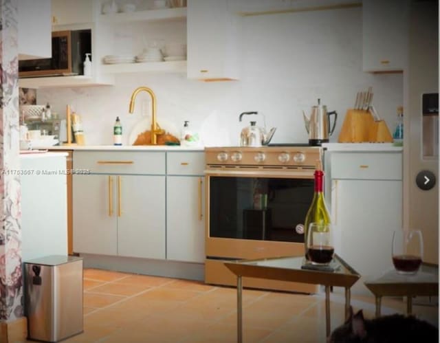 kitchen with open shelves, light tile patterned floors, light countertops, appliances with stainless steel finishes, and a sink