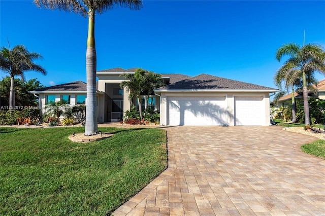 prairie-style home with decorative driveway, a front lawn, and stucco siding