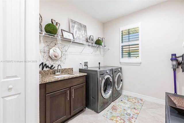 clothes washing area featuring baseboards, a sink, cabinet space, and washer and dryer