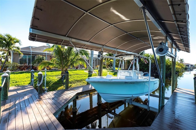 view of dock with a water view, boat lift, and a yard