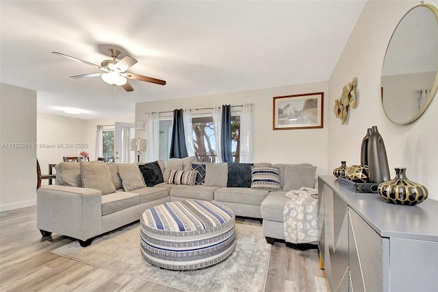 living area featuring light wood-style floors, baseboards, and a ceiling fan