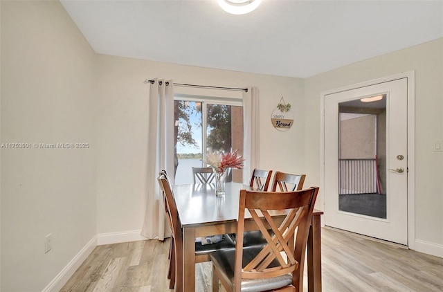 dining space with baseboards and light wood finished floors