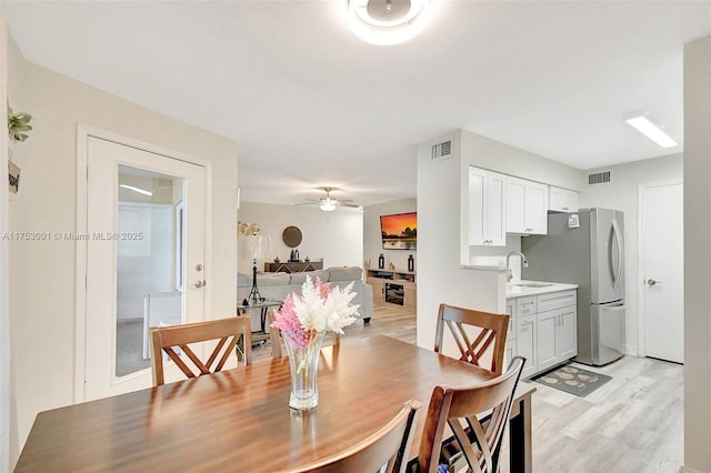 dining area featuring light wood-style floors, visible vents, and a ceiling fan