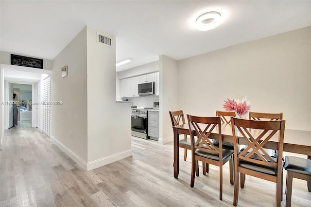 dining space featuring baseboards, visible vents, and light wood finished floors