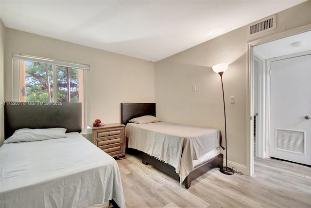 bedroom featuring light wood-style flooring, visible vents, and baseboards