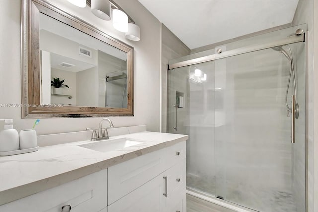 full bathroom with a stall shower, vanity, and visible vents