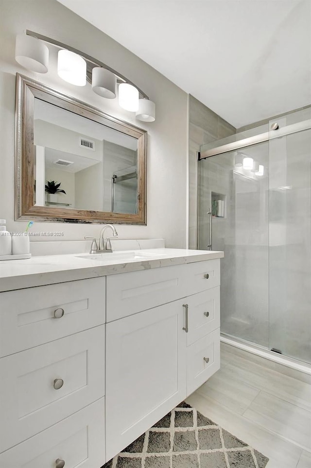 full bathroom featuring a shower stall, visible vents, and vanity