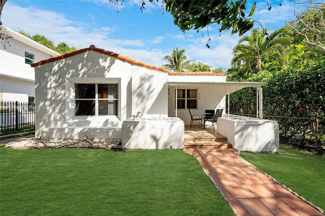 back of property featuring fence, a tiled roof, a lawn, and stucco siding