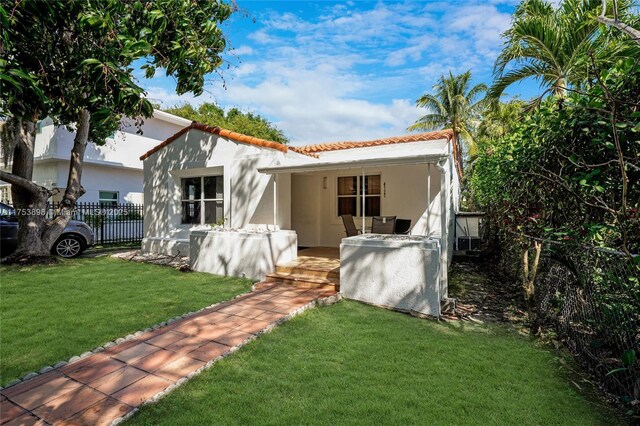 view of front of home with a tiled roof, a front yard, fence, and stucco siding