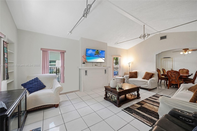 living room with lofted ceiling, visible vents, ceiling fan, and light tile patterned flooring