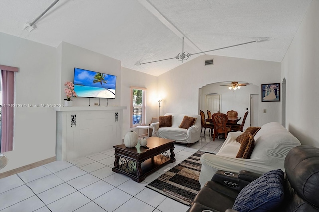 living room featuring arched walkways, lofted ceiling, visible vents, a ceiling fan, and light tile patterned flooring