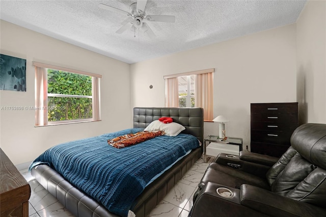 bedroom with marble finish floor, multiple windows, ceiling fan, and a textured ceiling