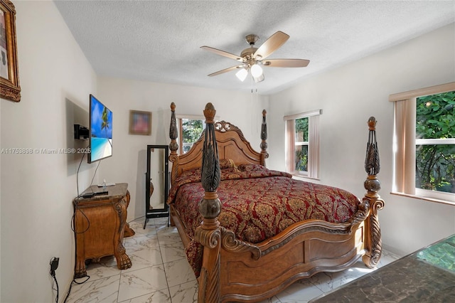 bedroom featuring a ceiling fan, a textured ceiling, multiple windows, and marble finish floor