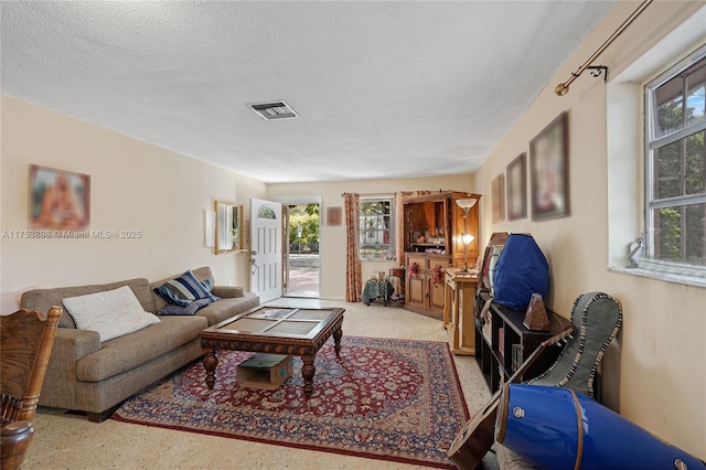 living room with visible vents, a textured ceiling, and speckled floor