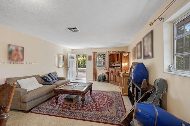 living room with visible vents, a healthy amount of sunlight, a textured ceiling, and speckled floor