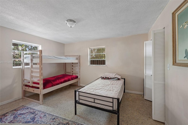 bedroom featuring a textured ceiling, speckled floor, and multiple windows