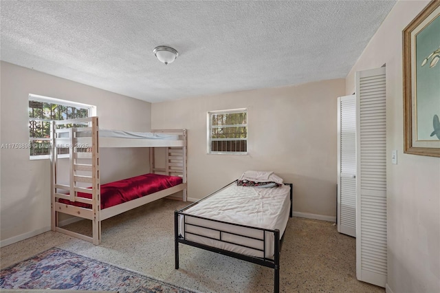 bedroom with baseboards, a textured ceiling, and speckled floor