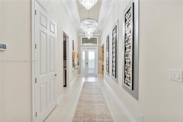 hallway with a chandelier, french doors, ornamental molding, and light tile patterned floors