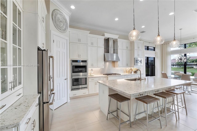 kitchen with tasteful backsplash, stainless steel appliances, crown molding, wall chimney range hood, and a sink