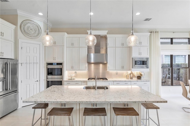 kitchen with tasteful backsplash, wall chimney exhaust hood, stainless steel appliances, a kitchen bar, and a sink